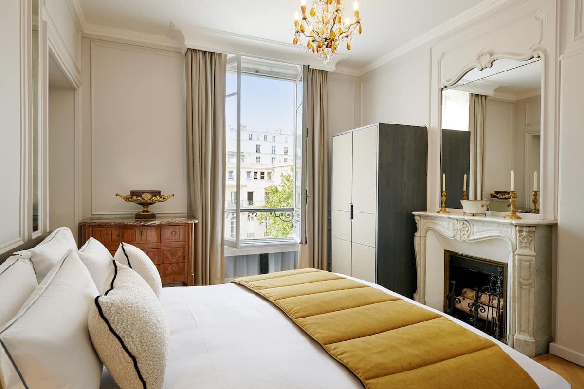 Una habitación de hotel con una cama grande, un aparador, un espejo y una chimenea.