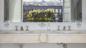 Ein Badezimmer mit zwei Waschbecken, einem Spiegel und Blick auf eine Stadtlandschaft durch ein Fenster.