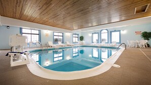An indoor swimming pool with clear blue water, surrounded by white lounge chairs and tables. - Best Western Pontiac Inn (Pontiac)