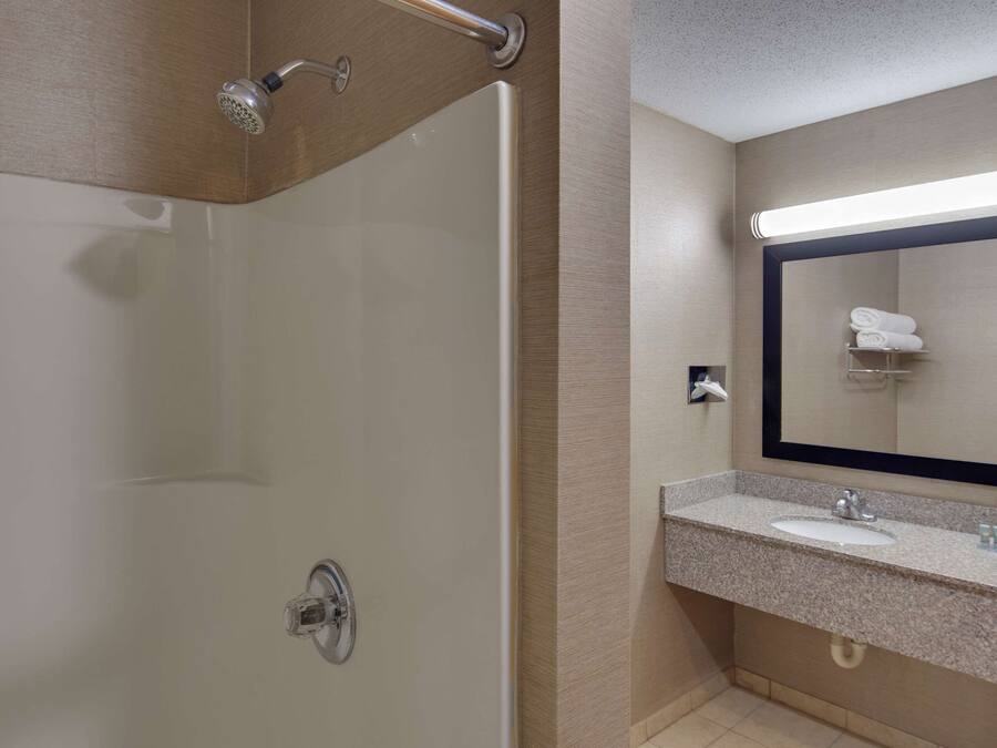 Un bagno moderno con doccia in vetro, uno specchio ampio e un piano di lavoro in granito con lavabo.