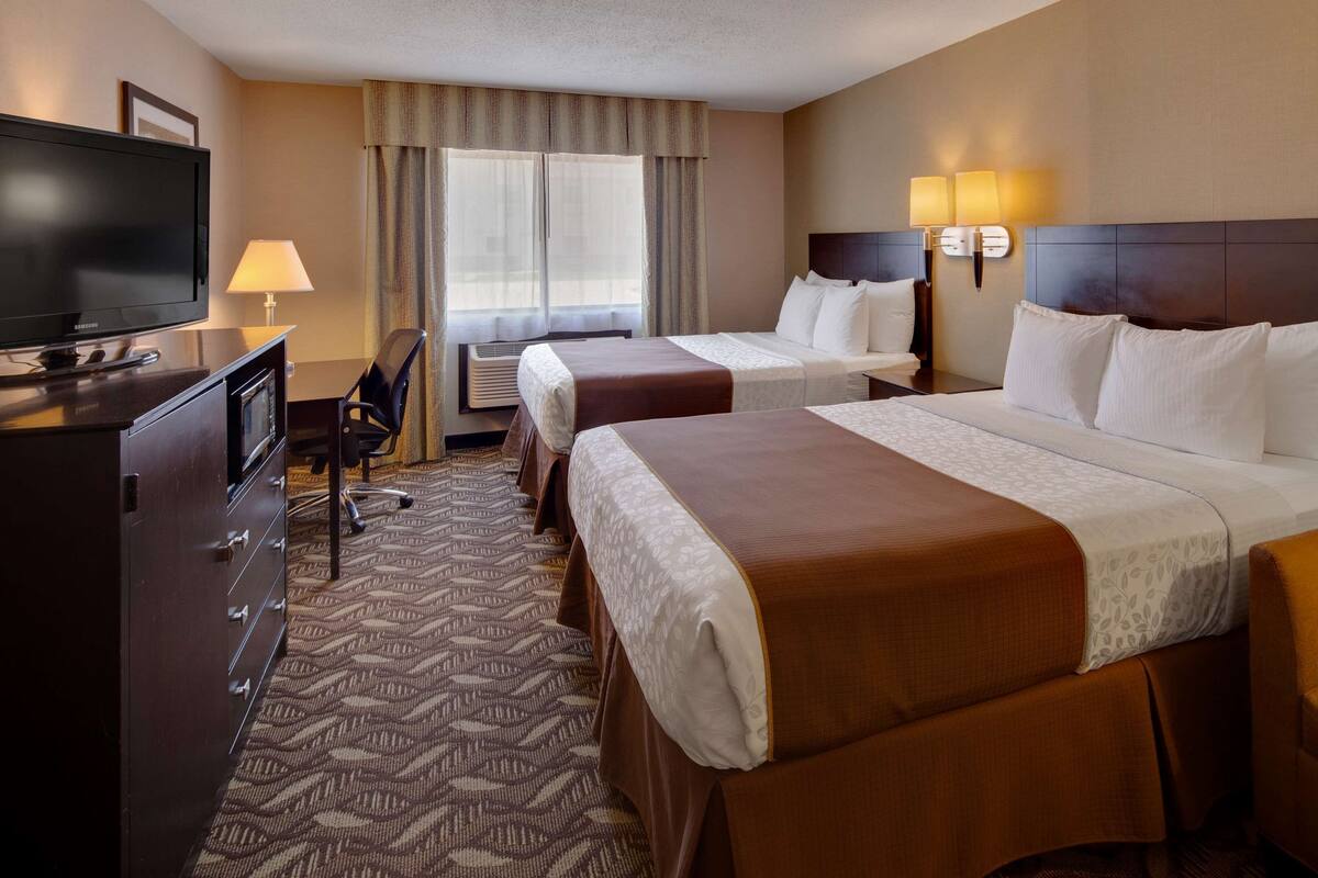 A hotel room with two beds, a TV, a desk, and a chair.