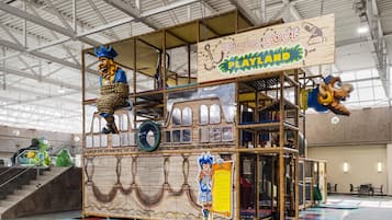 A pirate-themed play area with a ship structure, climbing nets, and a sign reading 'Pirates Cove Playland'.