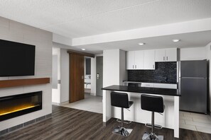 A modern kitchen with a black countertop, stainless steel appliances, and a flat-screen TV mounted on the wall. - Birchwood Inn, BW Premier Collection (Winnipeg)