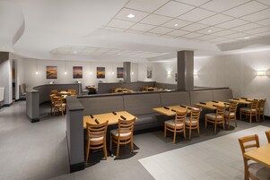 Un restaurante moderno con una zona de comedor central, mesas individuales y una barra.