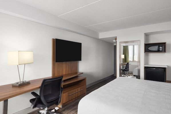A hotel room with a bed, a desk with a chair, a television, a microwave, and a small refrigerator. - Birchwood Inn, BW Premier Collection (Winnipeg)