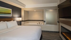 Habitación de hotel con una cama grande, baño privado con bañera, televisor de pantalla plana y un felpudo a rayas de cebra.