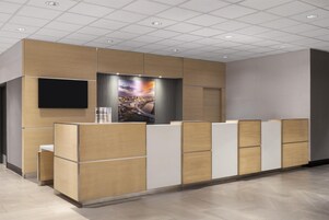 Un área de recepción con diseño moderno, que presenta un mostrador de madera, un televisor de pantalla plana y un cartel con vista a la ciudad.