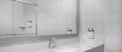 A modern bathroom with a white sink, a large mirror, and two Dove hand soap dispensers on the wall.