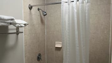 A shower area with a glass door, a towel rack with two white towels, and a soap dish.