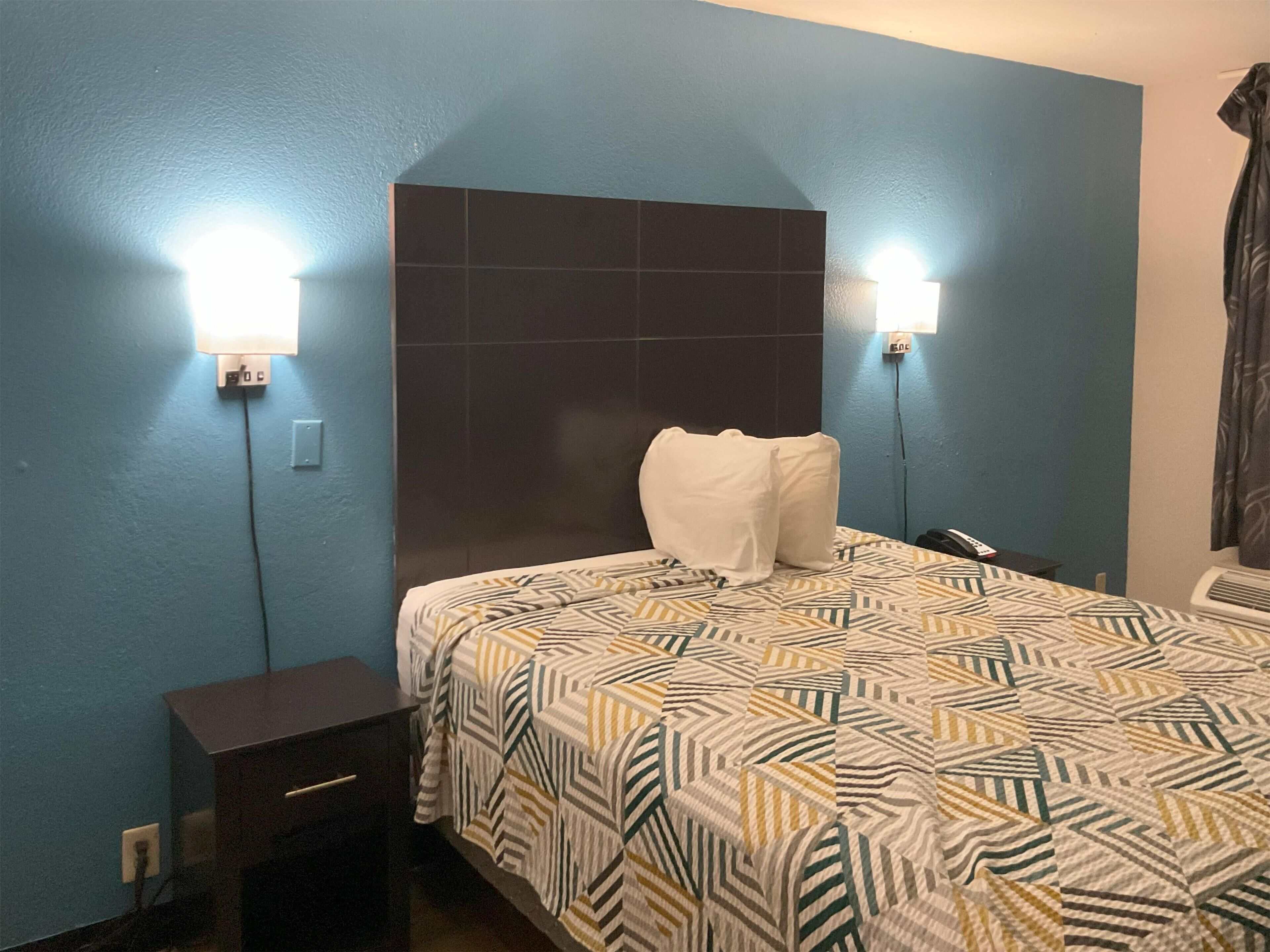 Une chambre d’hôtel avec un lit, deux lampes de chevet, une table de chevet et un téléphone.