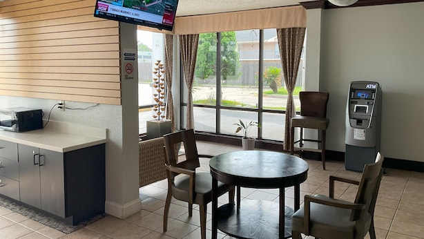 A restaurant with a TV displaying weather information, a no smoking sign, a cash register, and a seating area with chairs and a table.