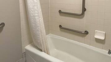 A bathroom with a white bathtub, grab bars, and a white shower curtain.