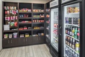Un présentoir proposant des collations et des boissons dans un magasin où sont également vendus divers produits emballés, ainsi qu’une section réfrigérée.