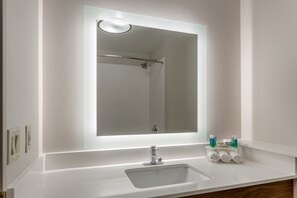 Une salle de bain avec un grand miroir, un lavabo et un porte-serviettes avec des serviettes.