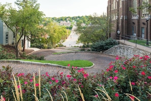 A paved courtyard with a curved walkway, surrounded by trees and flowering plants. - Holiday Inn Express Hotel & Suites Burlington by IHG (Burlington)