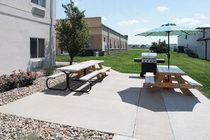 An outdoor patio with picnic tables and a barbecue grill. - Holiday Inn Express Hotel & Suites Burlington by IHG (Burlington)
