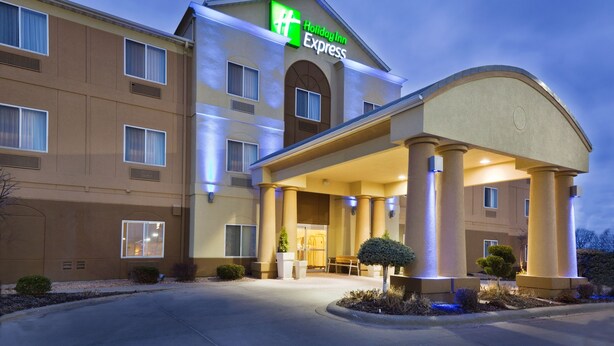 Un hotel Holiday Inn Express con entrada cubierta, varias ventanas y fachada bien iluminada.