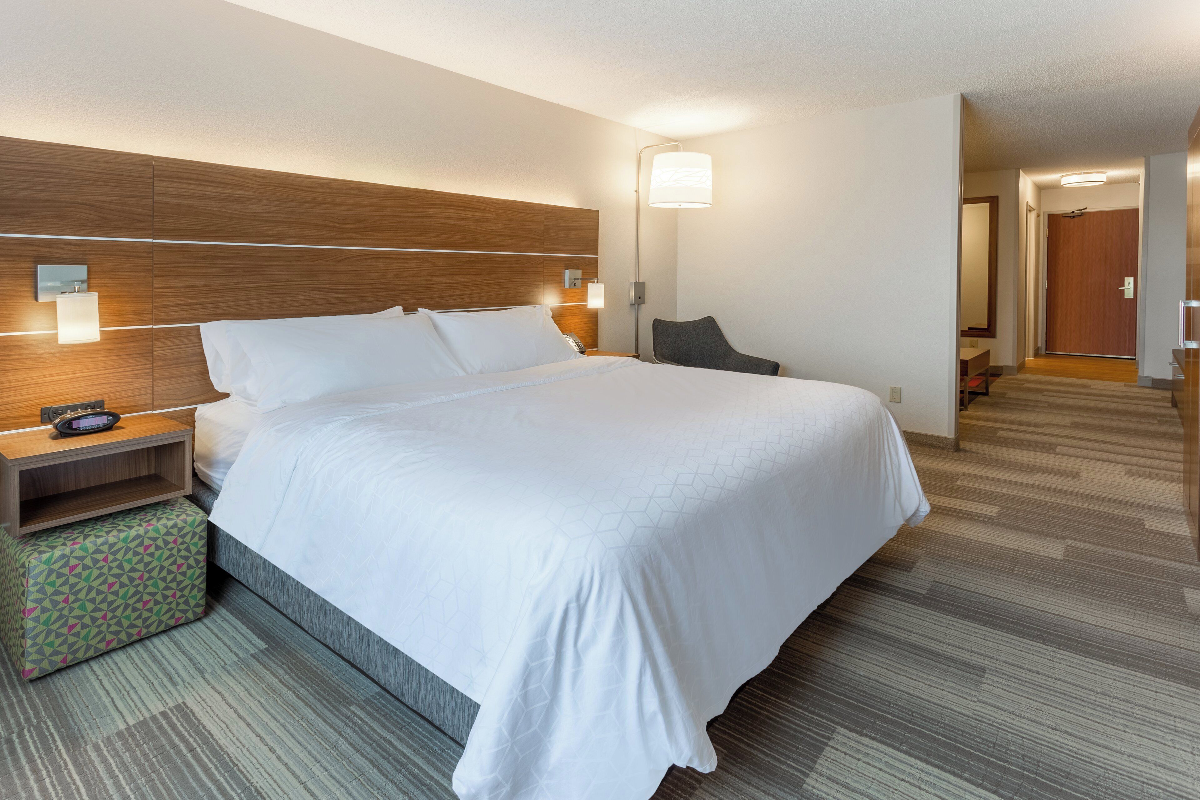 Une chambre d’hôtel avec un grand lit, des tables de chevet, une lampe et une chaise.