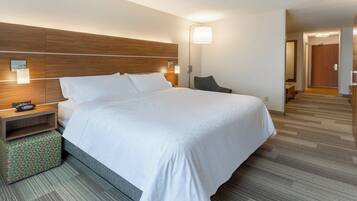 A hotel room with a large bed, bedside tables, a lamp, and a chair.