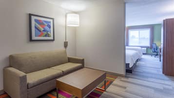 A hotel room with a sofa, a coffee table, a bed, a desk, and a window with a view.