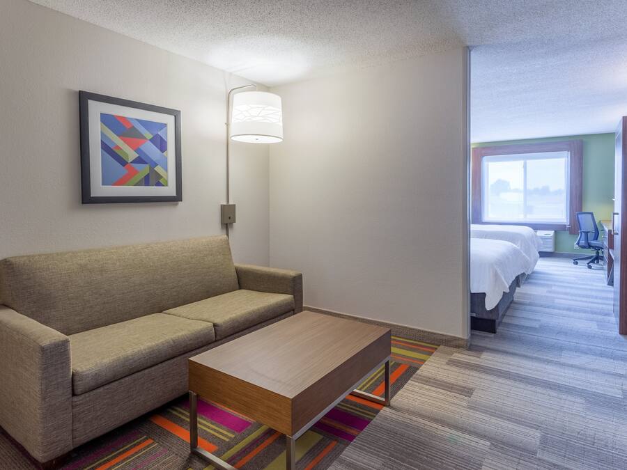 A hotel room with a sofa, a coffee table, a bed, a desk, and a window with a view.