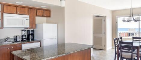 A modern kitchen with granite countertops, wooden cabinets, a built-in microwave, and a coffee maker.