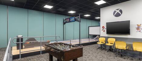 A room with a foosball table, a television, and seating area.
