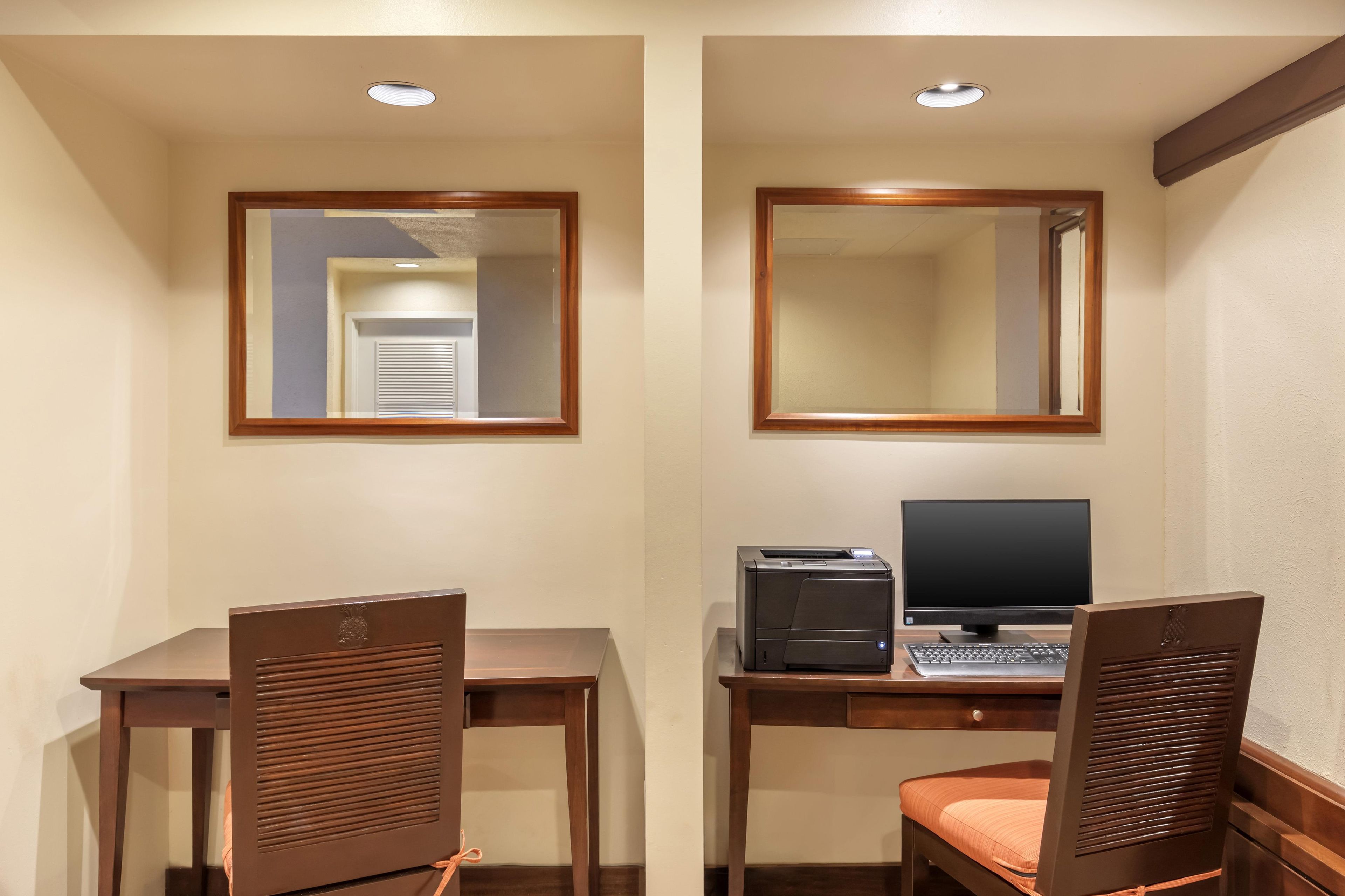 Een hotelkamer met een bureau, twee stoelen, een computer en een printer.