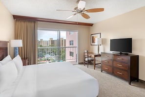 A hotel room with a large bed, a television, a desk, and a balcony with a view of buildings. - Hilton Vacation Club Ka'anapali Beach Maui (Kaanapali)