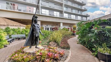 Eine Statue in einer angelegten Grünfläche, im Hintergrund ein Gebäude.