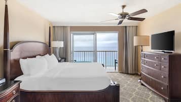 Habitación de hotel con una cama grande, televisión, cómoda y balcón con vista al mar.