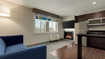 A modern kitchen with dark wooden cabinets, a built-in microwave, and a fireplace.