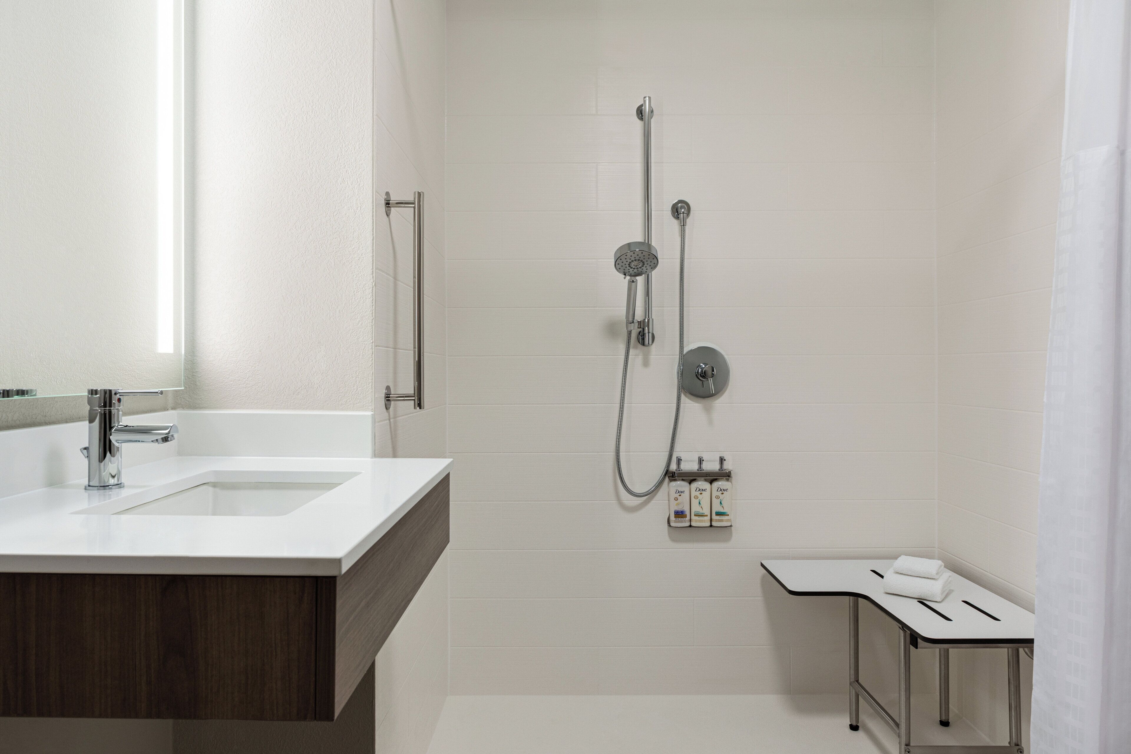 A modern bathroom with a white sink, a shower with a handheld showerhead, and a towel rack.