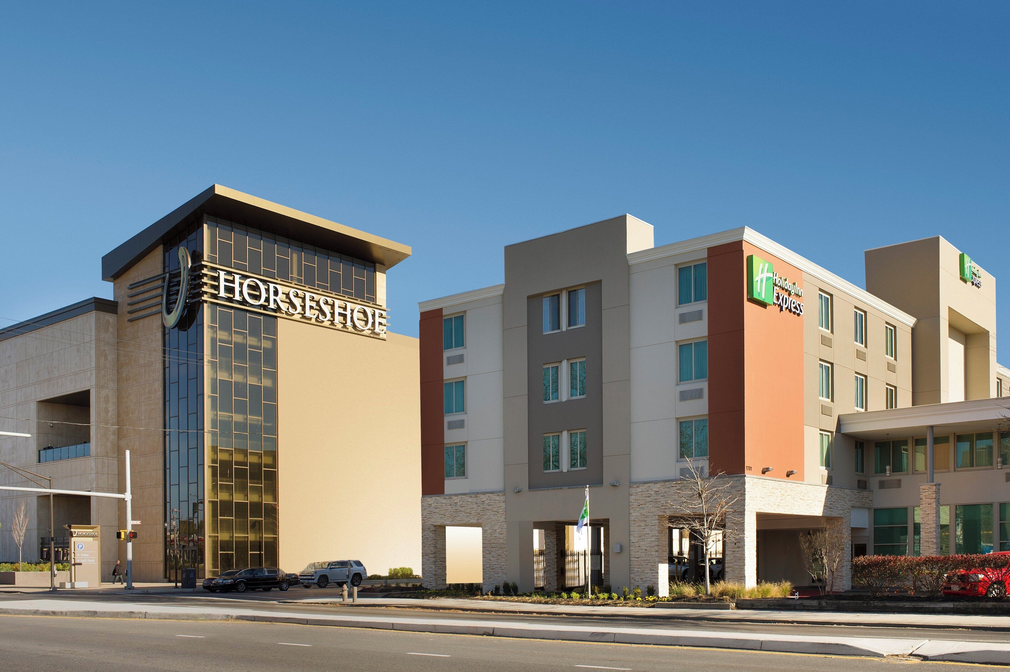 A multi-story hotel with a prominent 'HORSESHOE' sign on the left, a 'Holiday Inn Express' sign on the right, and a parking lot in the foreground.