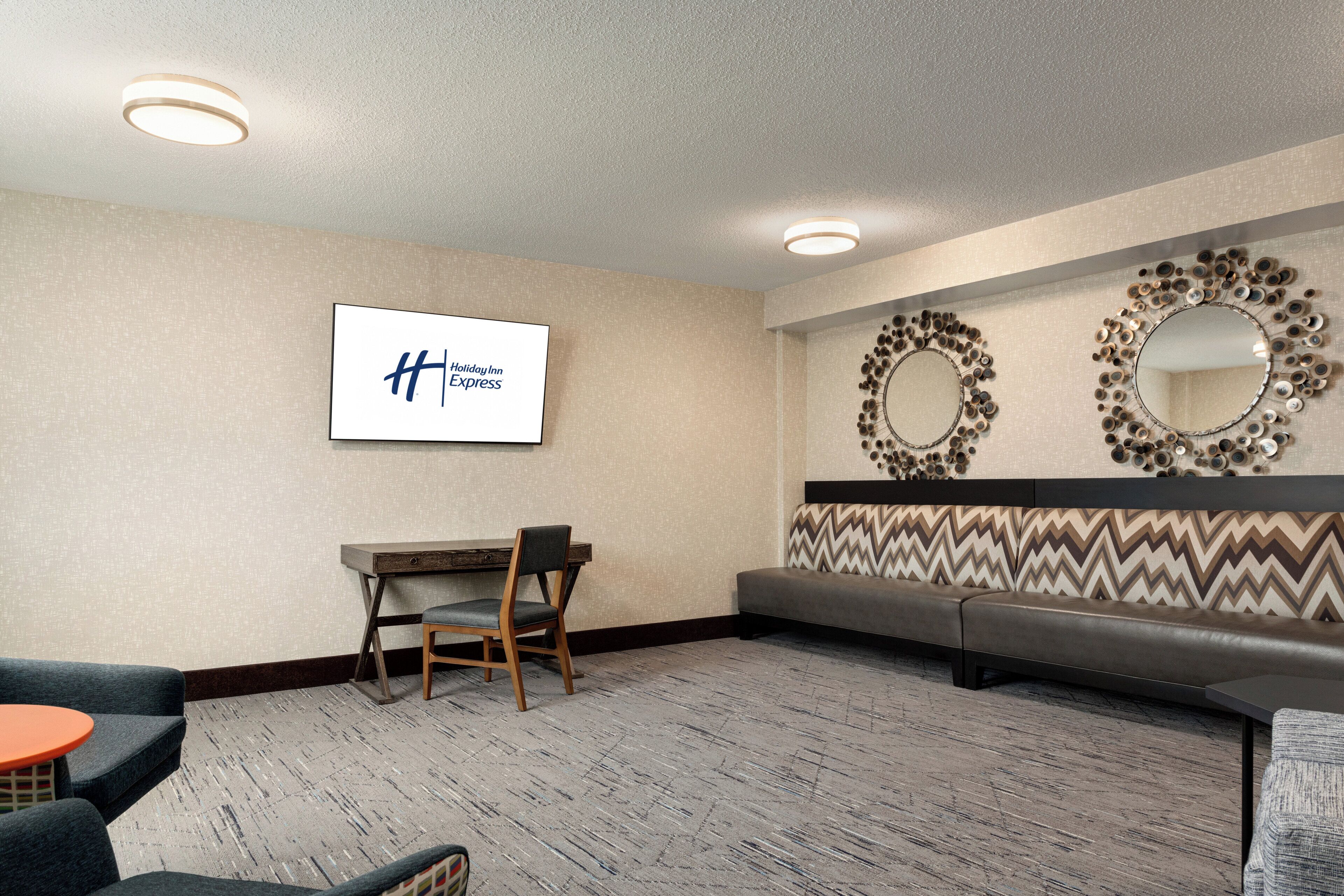 A hotel lobby with a reception desk, seating area, and decorative wall mirrors.