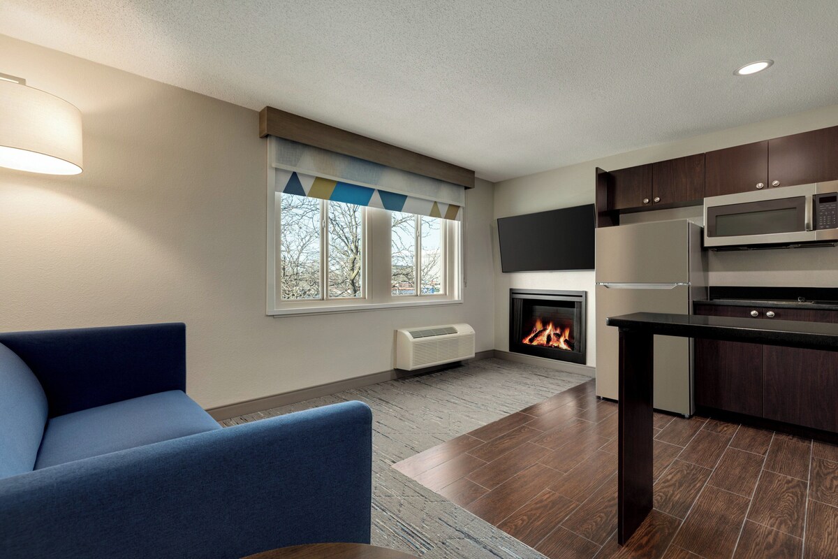 Una cocina moderna con armarios de madera oscura, un microondas empotrado y una chimenea.