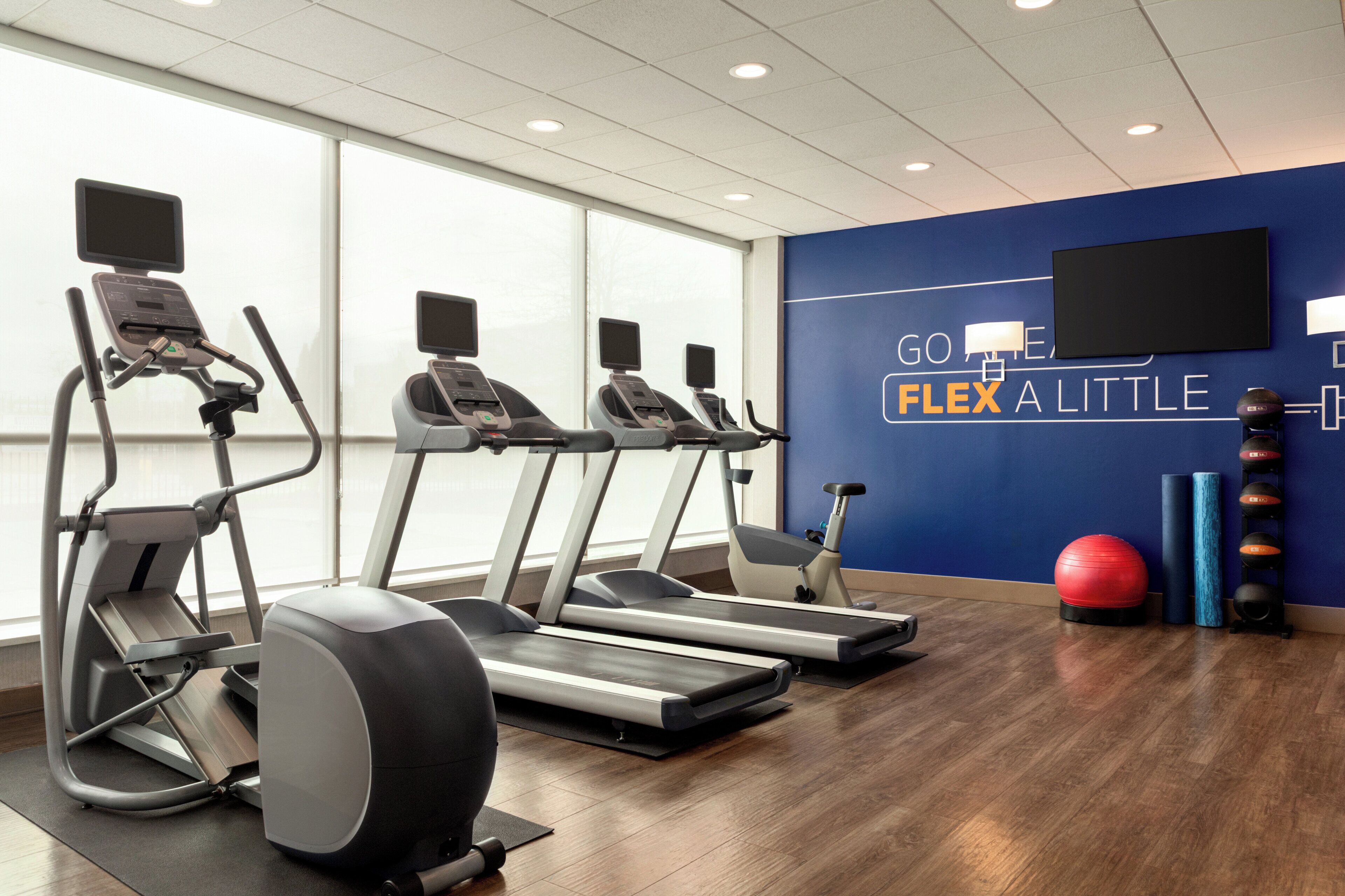 Un gimnasio con cintas de correr, elípticas y pelotas de ejercicio.