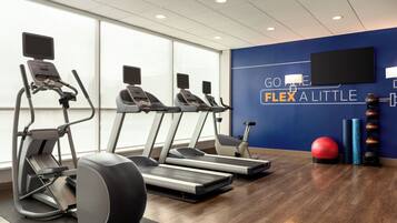 Un gimnasio con cintas de correr, elípticas y pelotas de ejercicio.