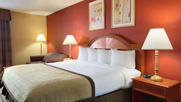 Une chambre d’hôtel avec un grand lit, deux lampes de chevet, une table de chevet et une tête de lit dotée d’un ventilateur.