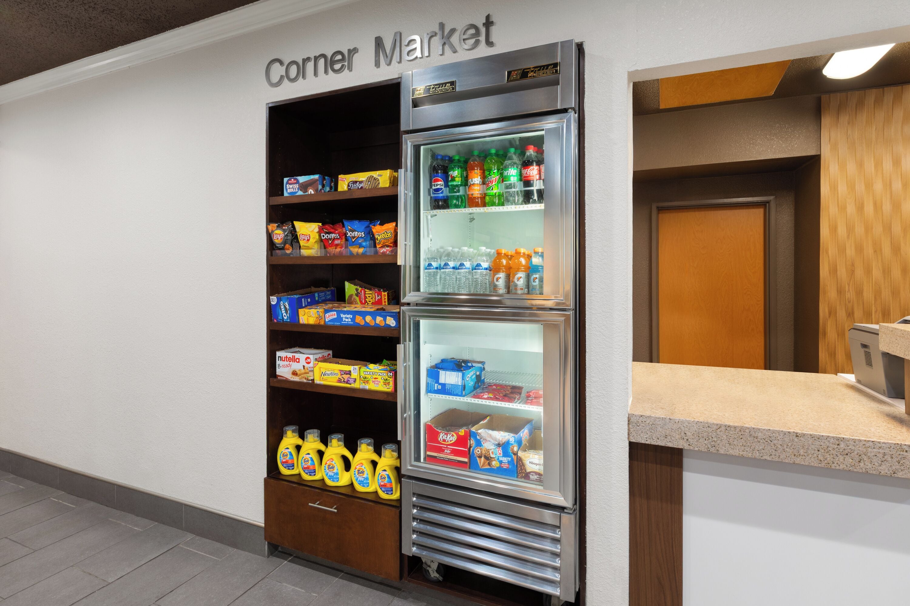 A corner market with a refrigerated display case stocked with beverages and snacks.