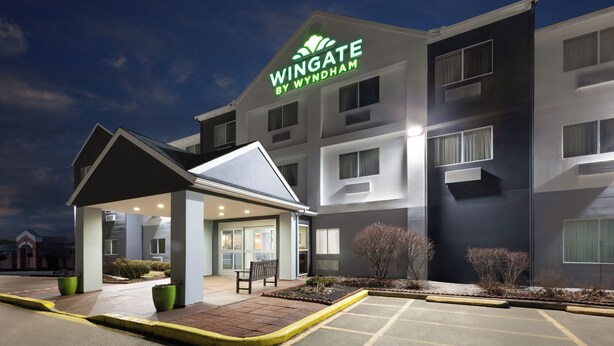 A Wingate by Wyndham hotel with a covered entrance, a parking lot, and a landscaped area with shrubs. - Wingate by Wyndham Marion (Marion)