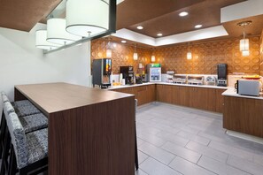 A modern kitchen with wooden cabinets, a central island, and a seating area with patterned chairs.