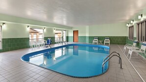 An indoor swimming pool with clear water, surrounded by white chairs and a tiled floor. - Wingate by Wyndham Marion (Marion)