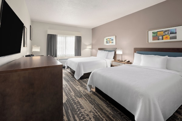 A hotel room with two beds, a desk, a TV, and a window with curtains. - Wingate by Wyndham Marion (Marion)