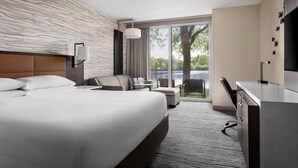 A modern hotel room with a large bed, a desk, a chair, and a view of the outdoors. - Lincolnshire Marriott Resort (Lincolnshire)