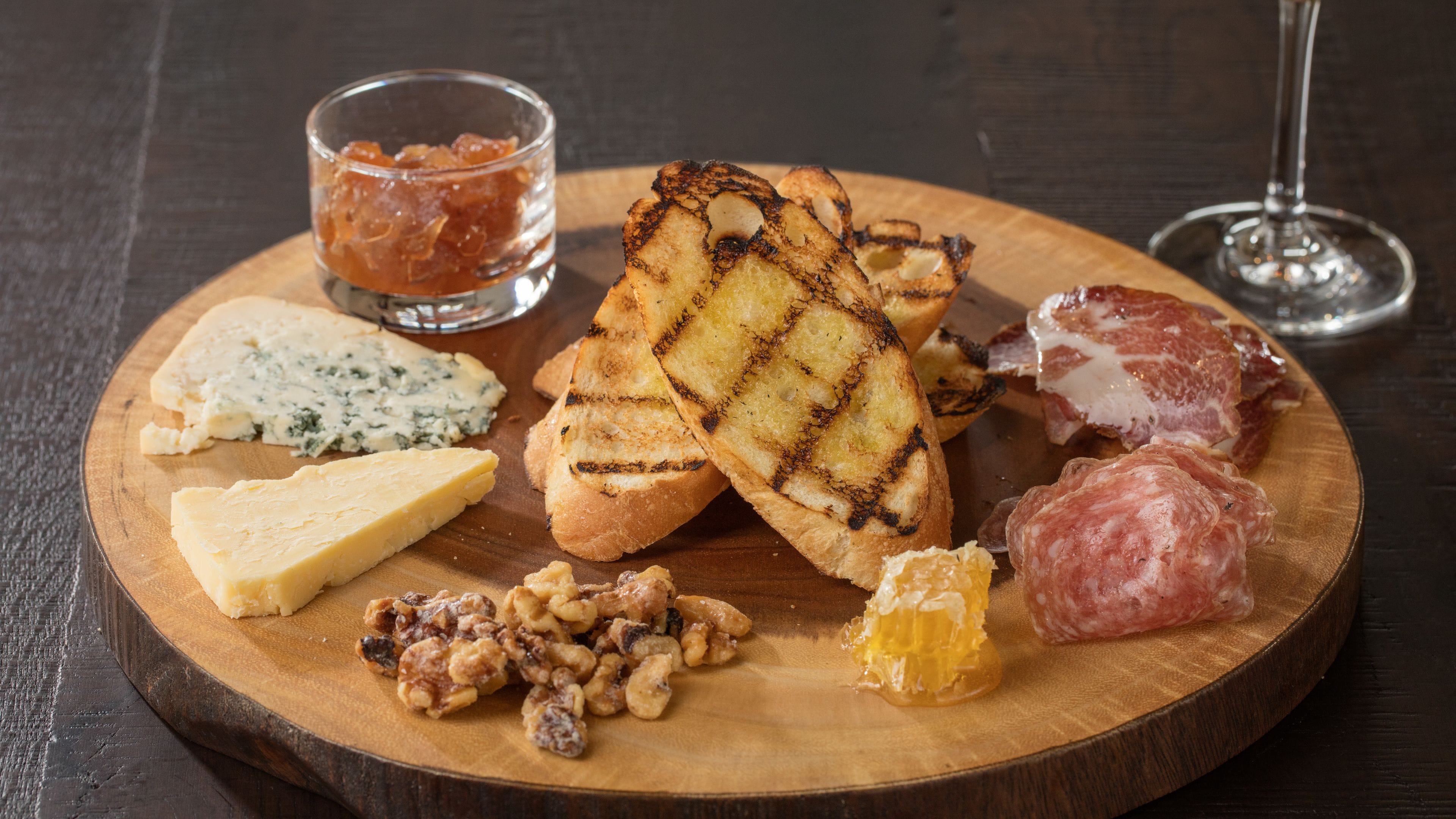 Une planche en bois garnie de différents fromages, de noix et de charcuteries.
