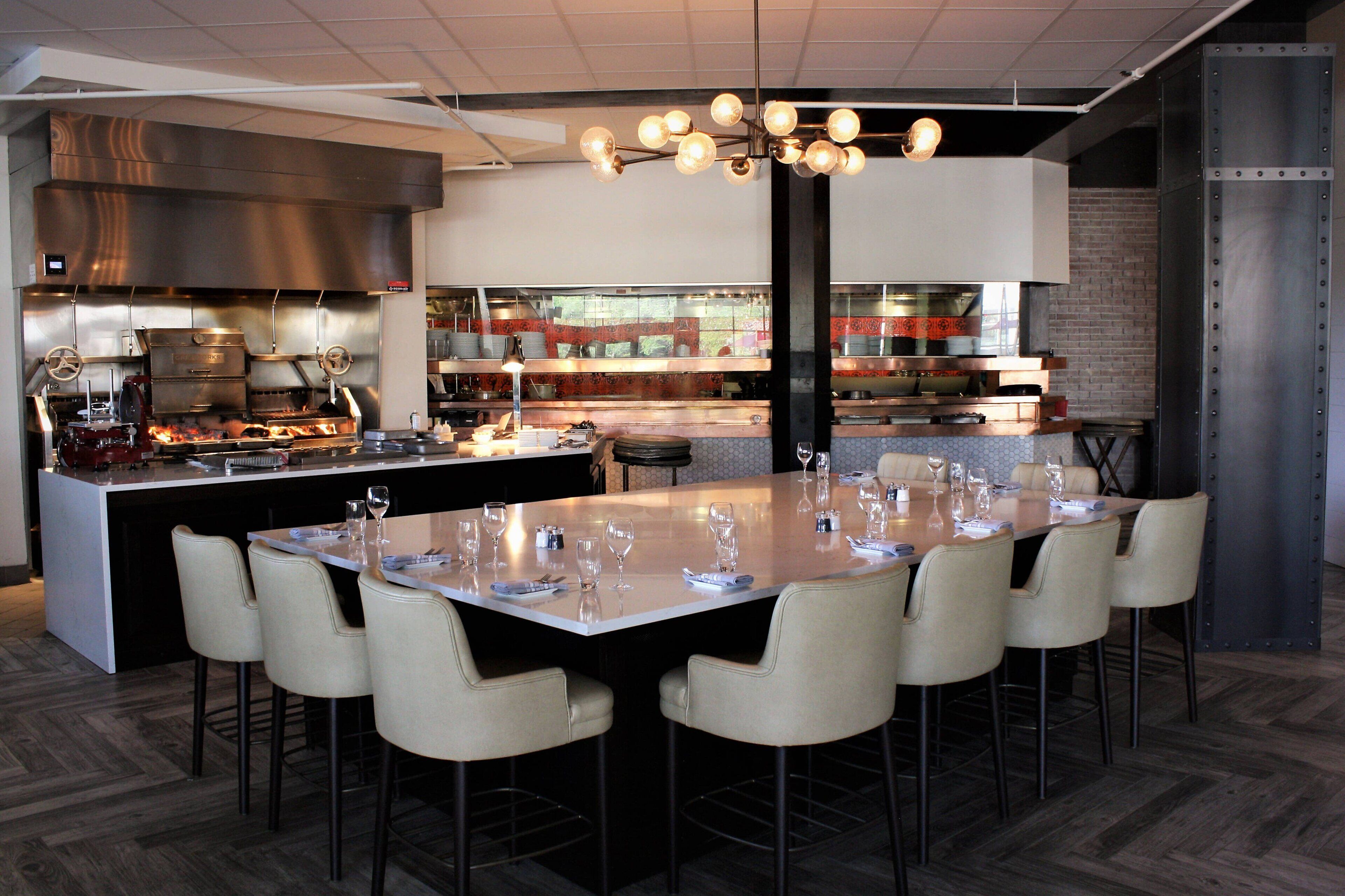 Une cuisine moderne dotée d’un îlot central, de tabourets de bar et d’une table à manger pouvant accueillir six personnes.