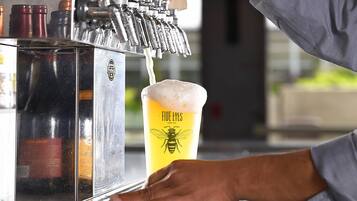 A hand operating a beer tap, pouring a beer into a glass labeled "FIVE EYES Honey Ale."
