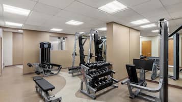 A gym with various exercise equipment including dumbbells, benches, and weight machines.