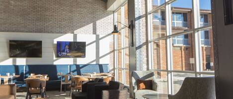 A modern restaurant with brick walls, large windows, and a variety of seating options including tables and chairs.